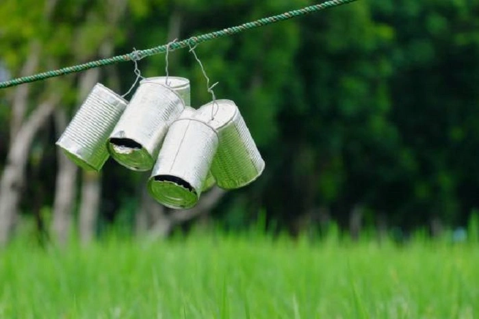 image of old tin cans hanging in lawn above the newly seeded area to keep birds away