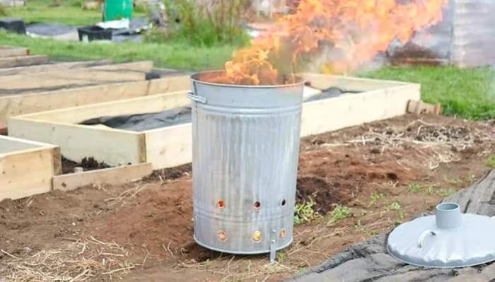image of a 55-gallon metal barrel having wet leaves burning inside it