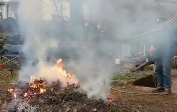 image of a gardener using a blower to initiate burning of wet leaves